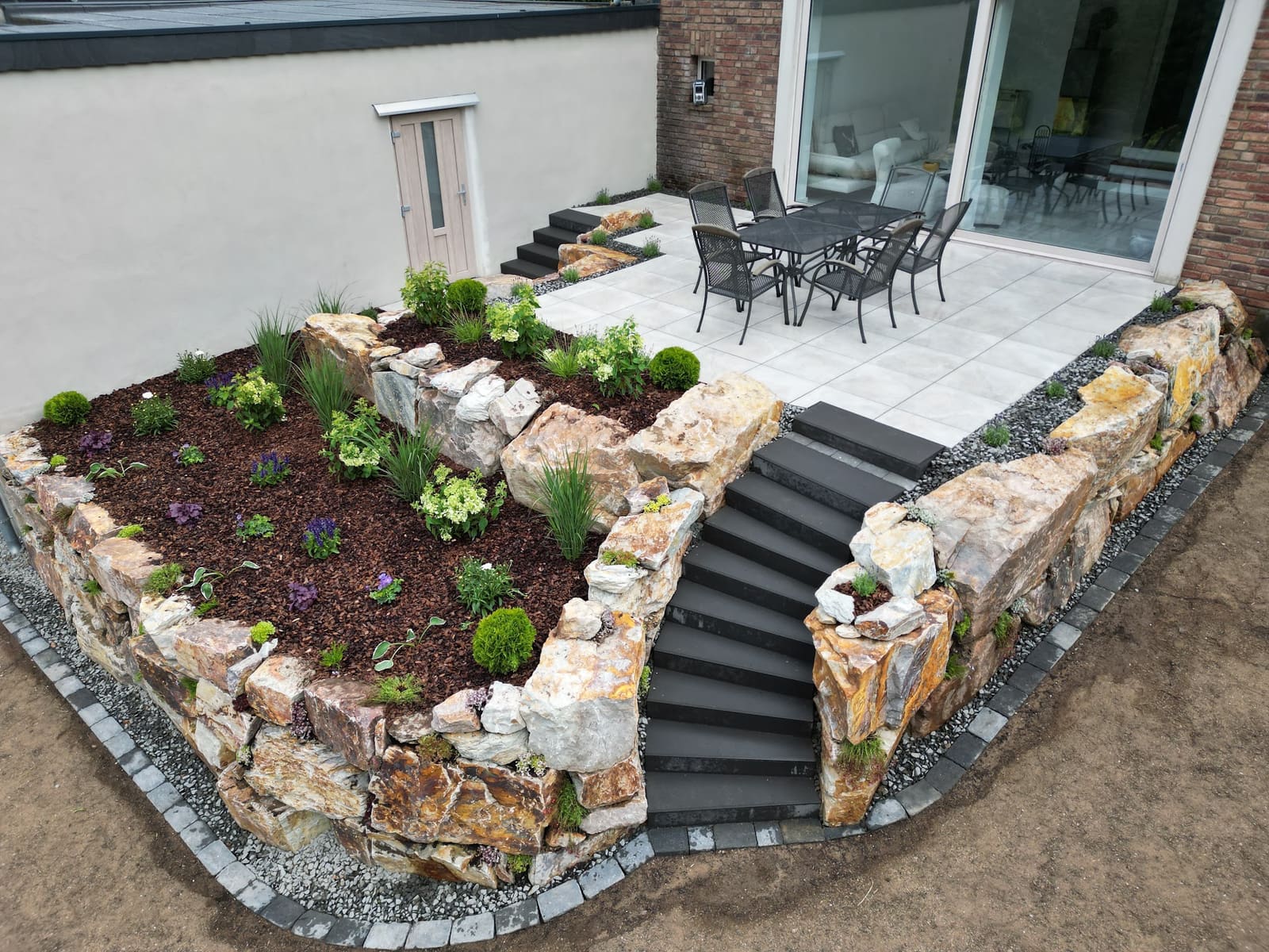 Naturstein-Trockenmauer mit Bepflanzung, Blockstufen und Terrasse in der Nordeifel